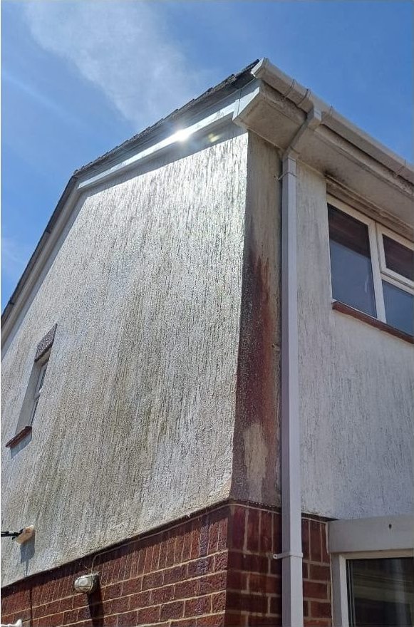Algae-stained render gable cleaned before and after in Lymington - before