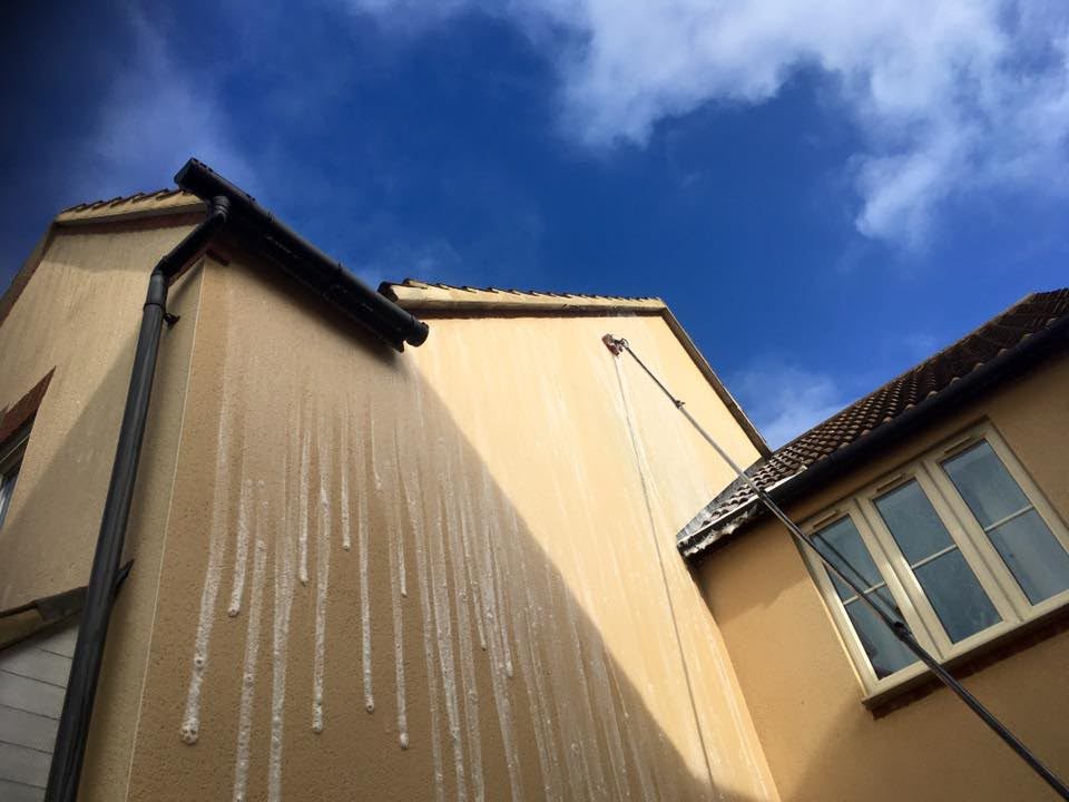Soft washing treatment being applied to a rendered wall in Lymington