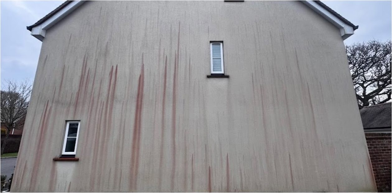 Red algae streaks removed from a rendered gable wall, before and after in Lymington - before